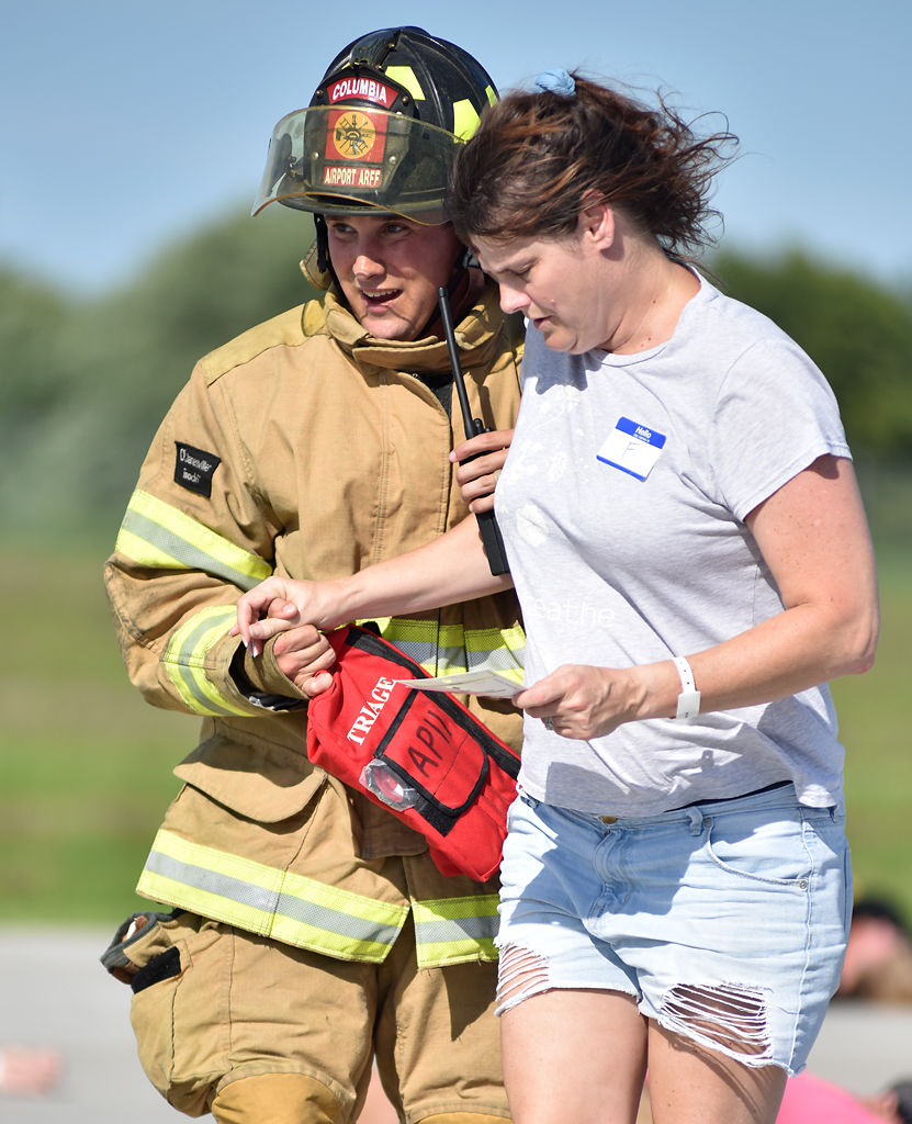 Firefighter Brady Sanger leads Michelle Seymoure away from the tarmac and other "victims"